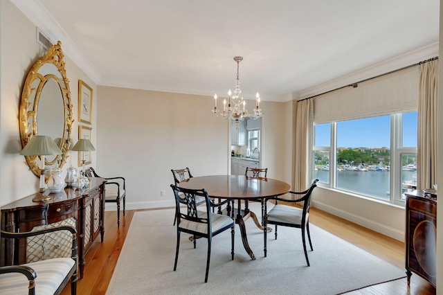 dining space with sink, light hardwood / wood-style flooring, a notable chandelier, a water view, and ornamental molding