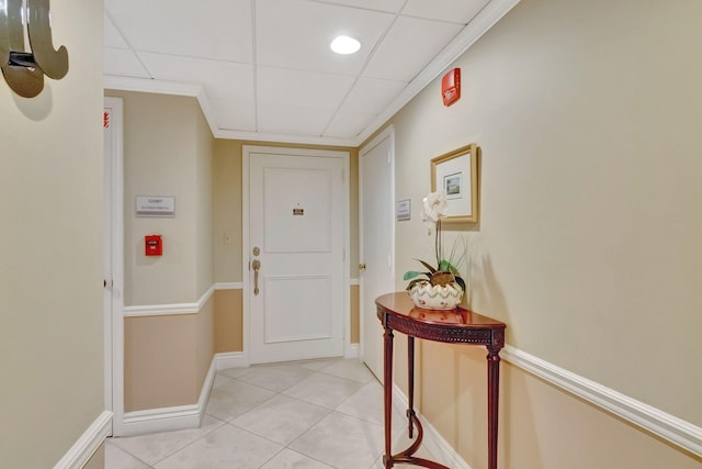 entryway featuring crown molding, a drop ceiling, and light tile patterned floors