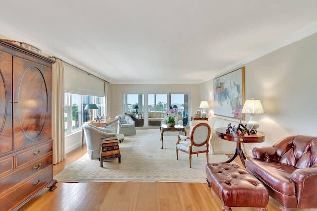 living room featuring crown molding, plenty of natural light, and light hardwood / wood-style flooring