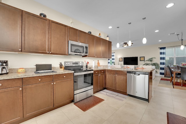 kitchen with pendant lighting, light tile patterned floors, stainless steel appliances, sink, and kitchen peninsula