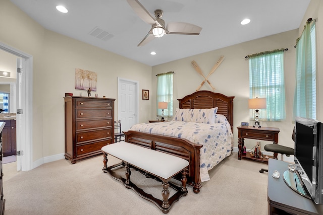 bedroom with ceiling fan, light carpet, and connected bathroom