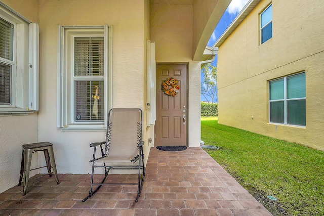 view of exterior entry featuring a patio area and a yard