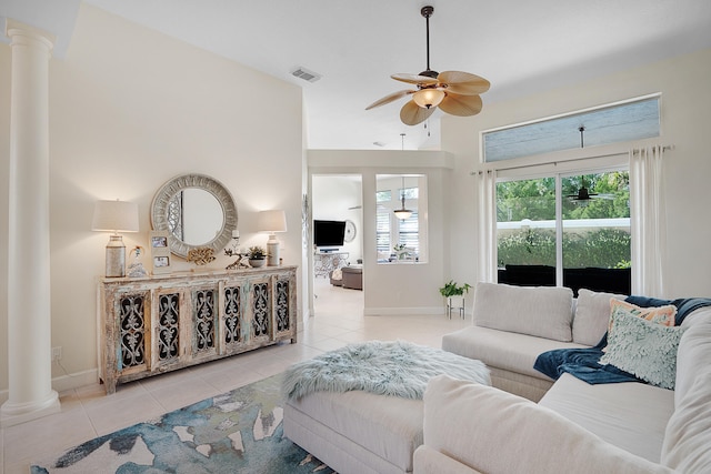 tiled living room with ceiling fan, a towering ceiling, and ornate columns