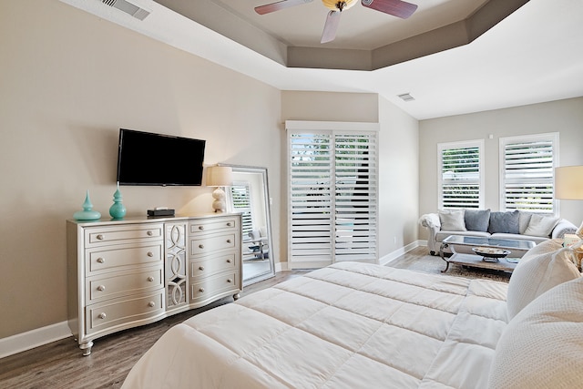 bedroom featuring light hardwood / wood-style flooring, a raised ceiling, and ceiling fan