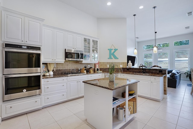 kitchen featuring a center island, kitchen peninsula, stainless steel appliances, and white cabinetry