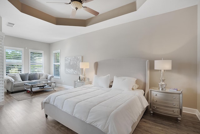 bedroom featuring a tray ceiling, ceiling fan, and dark hardwood / wood-style floors