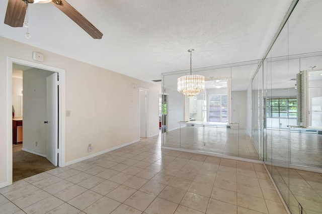 spare room featuring light tile patterned floors and ceiling fan with notable chandelier