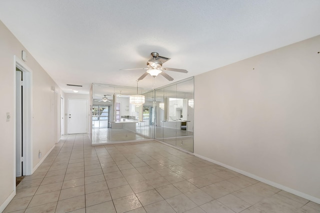 unfurnished room with a textured ceiling, light tile patterned floors, and ceiling fan