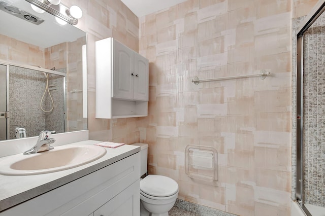 bathroom with vanity, toilet, tile walls, and walk in shower