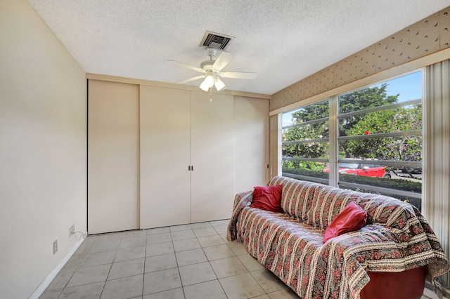 tiled living room featuring ceiling fan and a textured ceiling