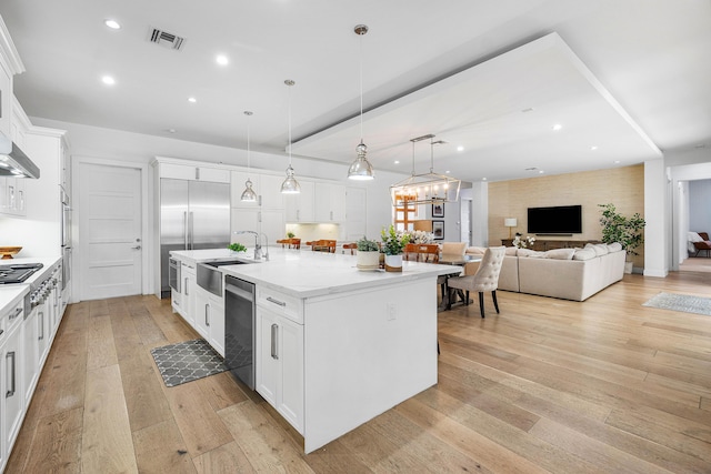 200 NE 6th Ct, Boca Raton, FL 33432 - kitchen featuring stainless steel appliances, a sink, light wood-style flooring, an island with sink, and white cabinets