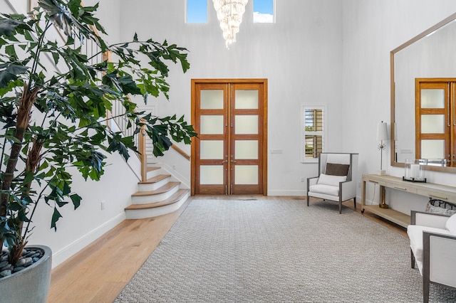 foyer entrance featuring a notable chandelier, a high ceiling, light hardwood / wood-style floors, and plenty of natural light