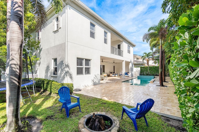 200 NE 6th Ct, Boca Raton, FL 33432 - rear view of house with a trampoline, a fire pit, stucco siding, ceiling fan, and a patio
