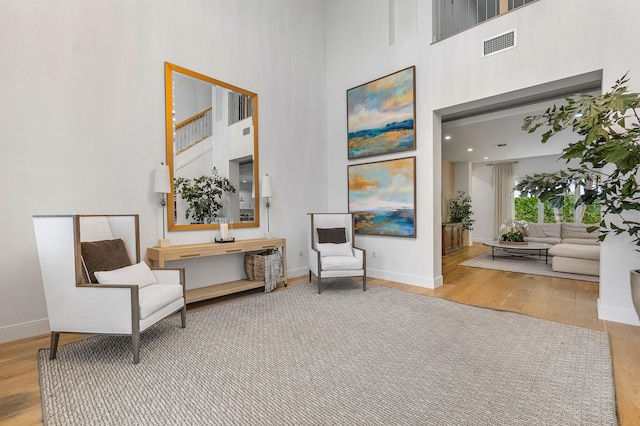 sitting room with light hardwood / wood-style floors and a high ceiling