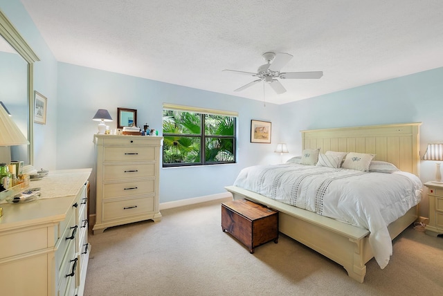 carpeted bedroom featuring ceiling fan and a textured ceiling