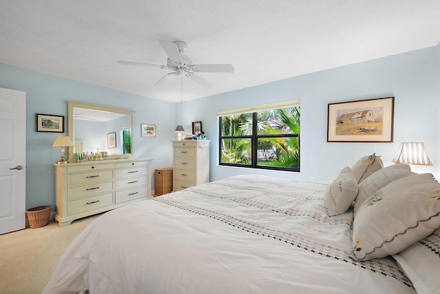 bedroom featuring ceiling fan, light carpet, and a textured ceiling