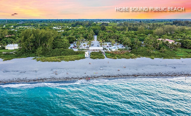 aerial view at dusk with a water view and a beach view