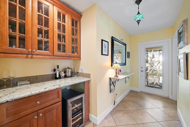 interior space with light stone countertops, light tile patterned floors, beverage cooler, and pendant lighting