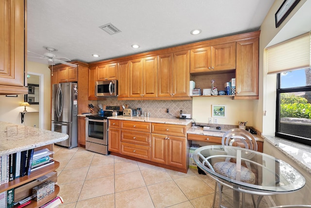 kitchen with light tile patterned flooring, light stone counters, and appliances with stainless steel finishes