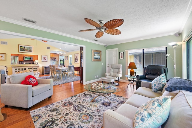 living room featuring crown molding, vaulted ceiling, ceiling fan, a textured ceiling, and wood-type flooring