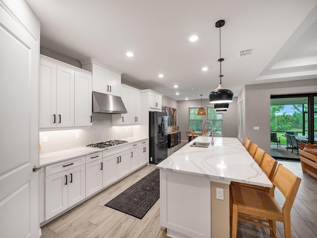 kitchen with a large island, plenty of natural light, sink, a breakfast bar area, and black fridge