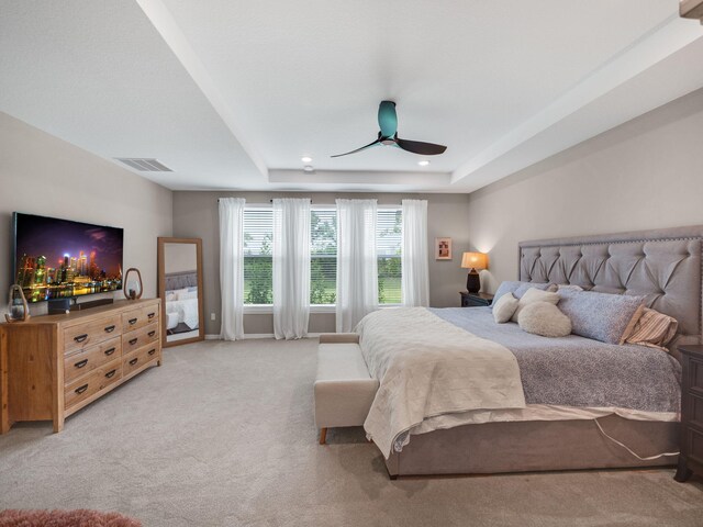 bedroom featuring light carpet, a raised ceiling, and ceiling fan