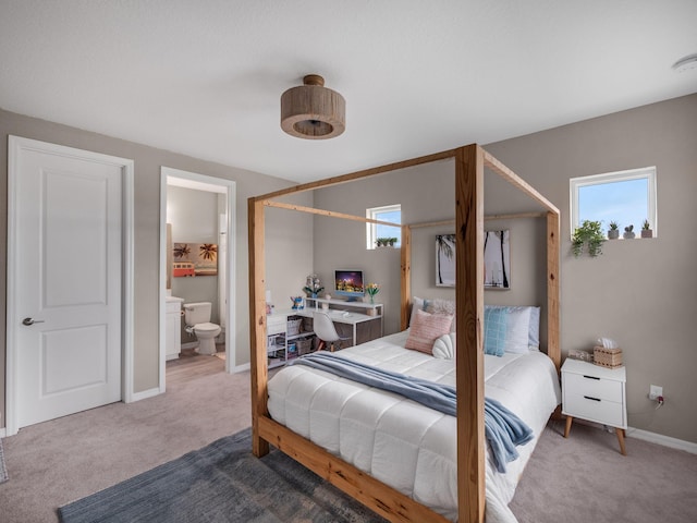 bedroom featuring ensuite bath, carpet floors, and multiple windows