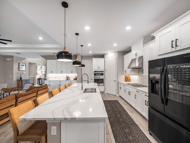 kitchen with a breakfast bar, stainless steel appliances, sink, ceiling fan, and a large island