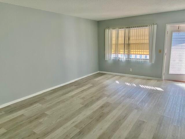 unfurnished room featuring baseboards, a textured ceiling, and wood finished floors