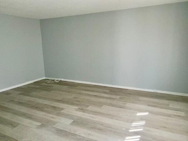 spare room with baseboards and wood finished floors