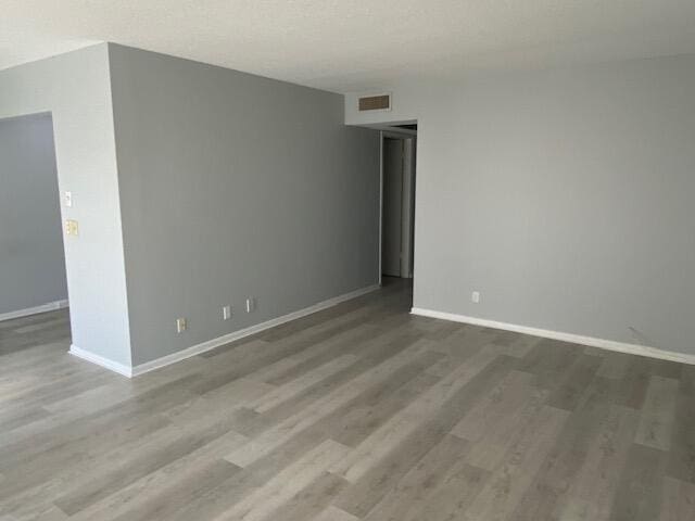 spare room with visible vents, baseboards, and wood finished floors