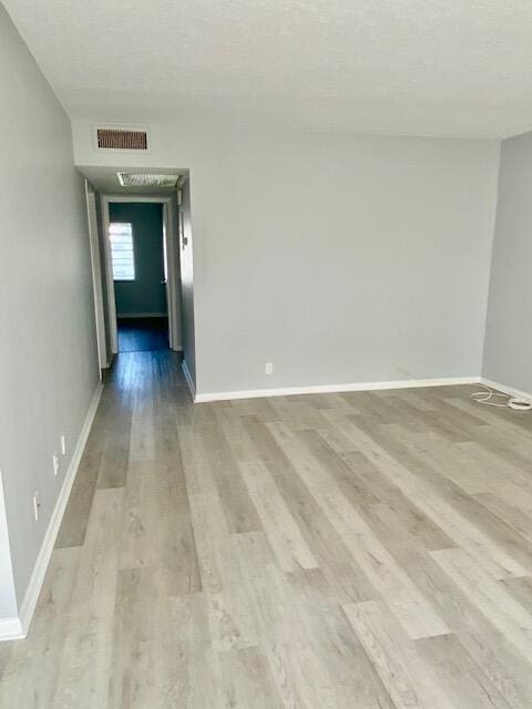 spare room featuring visible vents, baseboards, and wood finished floors