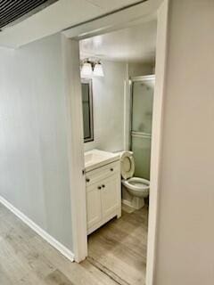 full bathroom with vanity, wood finished floors, baseboards, a stall shower, and toilet