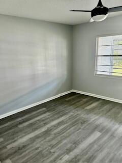 spare room featuring wood finished floors, baseboards, and ceiling fan