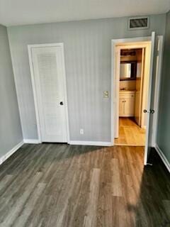 unfurnished bedroom with wood finished floors, visible vents, and baseboards