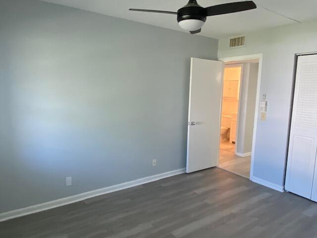 unfurnished bedroom with dark wood finished floors, visible vents, a ceiling fan, and baseboards