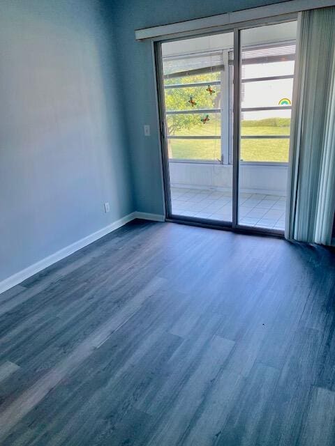 spare room with dark wood-type flooring, baseboards, and a wealth of natural light