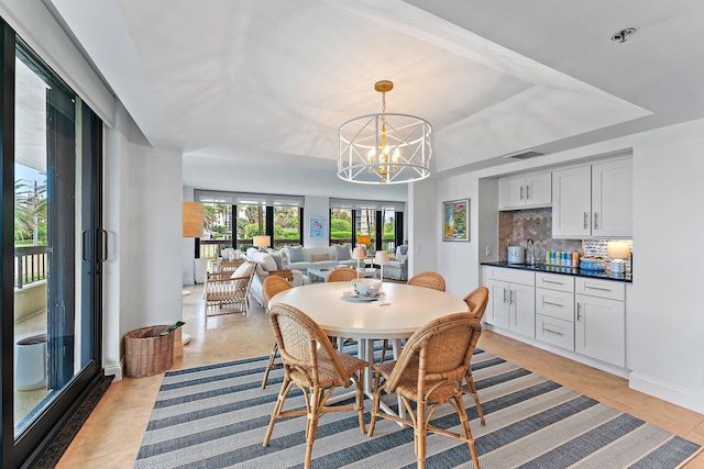 tiled dining space featuring a tray ceiling, sink, and an inviting chandelier