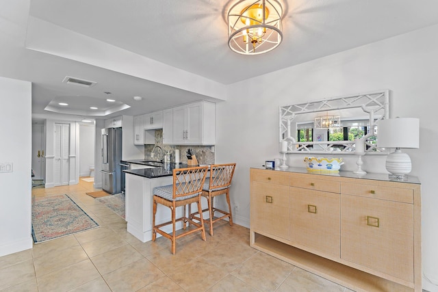 kitchen with a chandelier, sink, a tray ceiling, high end fridge, and a breakfast bar