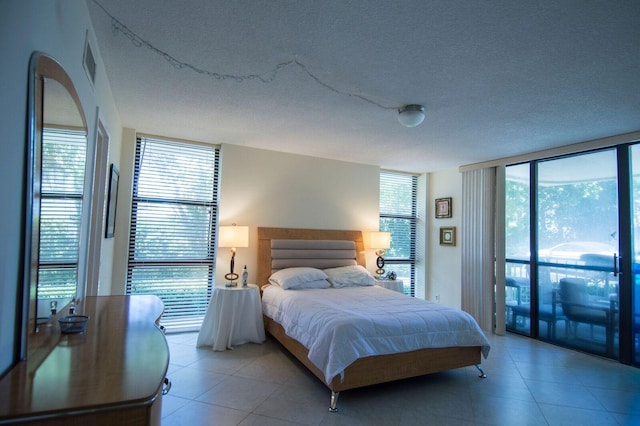 bedroom featuring a textured ceiling, a wall of windows, and access to outside