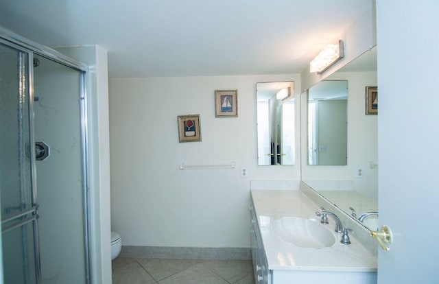 bathroom featuring vanity, toilet, tile patterned floors, and a shower with shower door