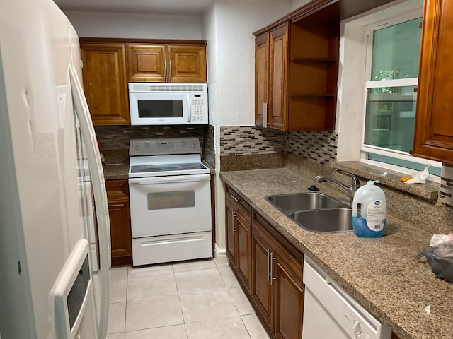 kitchen with white appliances, light tile patterned floors, backsplash, sink, and light stone counters