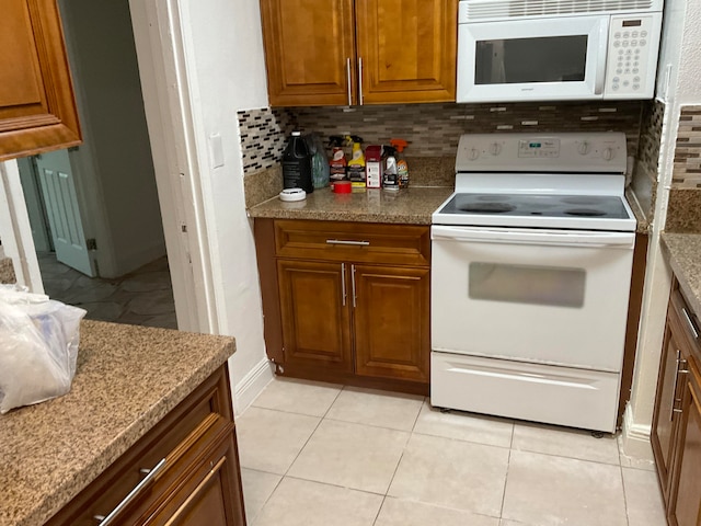 kitchen with white appliances, light tile patterned floors, and backsplash