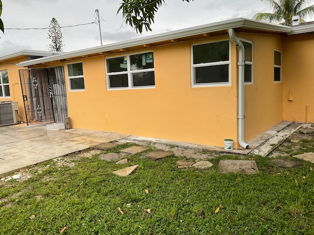 view of property exterior featuring cooling unit, a lawn, and a patio area