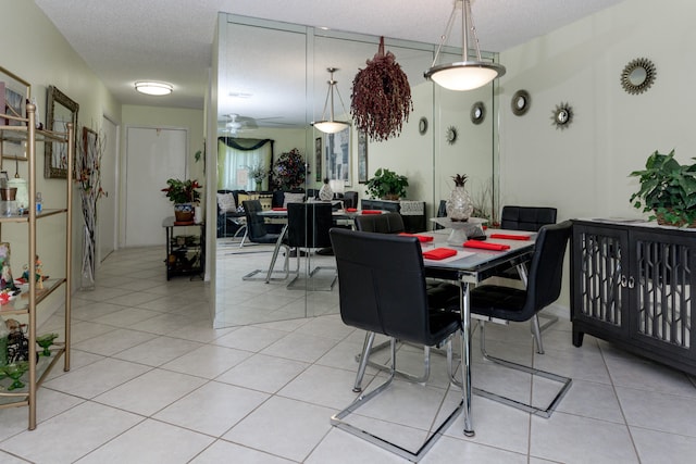 tiled dining space featuring a textured ceiling and ceiling fan