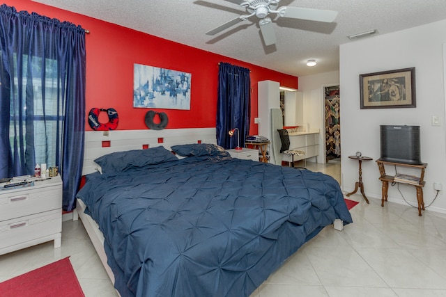 bedroom featuring ceiling fan, light tile patterned floors, and a textured ceiling