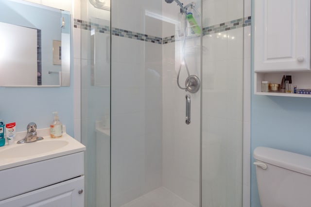 bathroom featuring vanity, toilet, and a shower with shower door