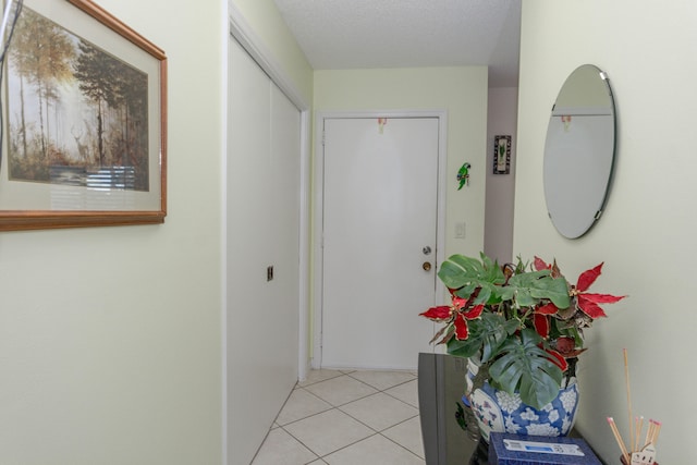 hall featuring light tile patterned flooring and a textured ceiling