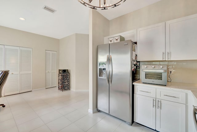 kitchen with tasteful backsplash, an inviting chandelier, stainless steel fridge with ice dispenser, and white cabinetry