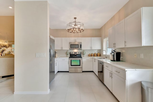 kitchen with white cabinetry, a chandelier, decorative light fixtures, stainless steel appliances, and sink